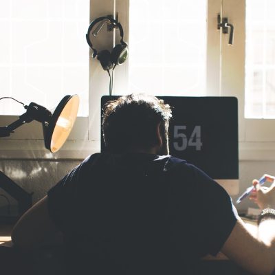 libtv 用户运营苏禾戴着耳机坐在电脑前处理读者来信，屏幕上是一封封纠错邮件，她一边读一边在便签上写下回复要点